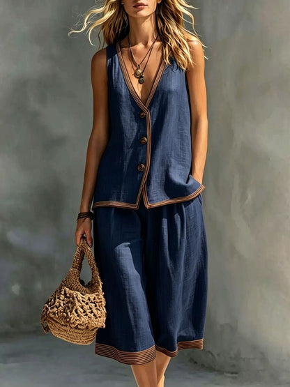Women's navy blue sleeveless buttoned vest and matching cropped wide-leg pants two-piece set featuring contrast trim detailing, modeled outdoors with a woven handbag.