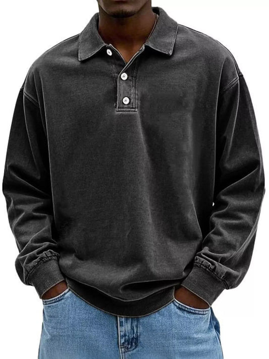 Man wearing a washed vintage black long-sleeve polo shirt with a collared henley neckline and three buttons, paired with light wash denim jeans.