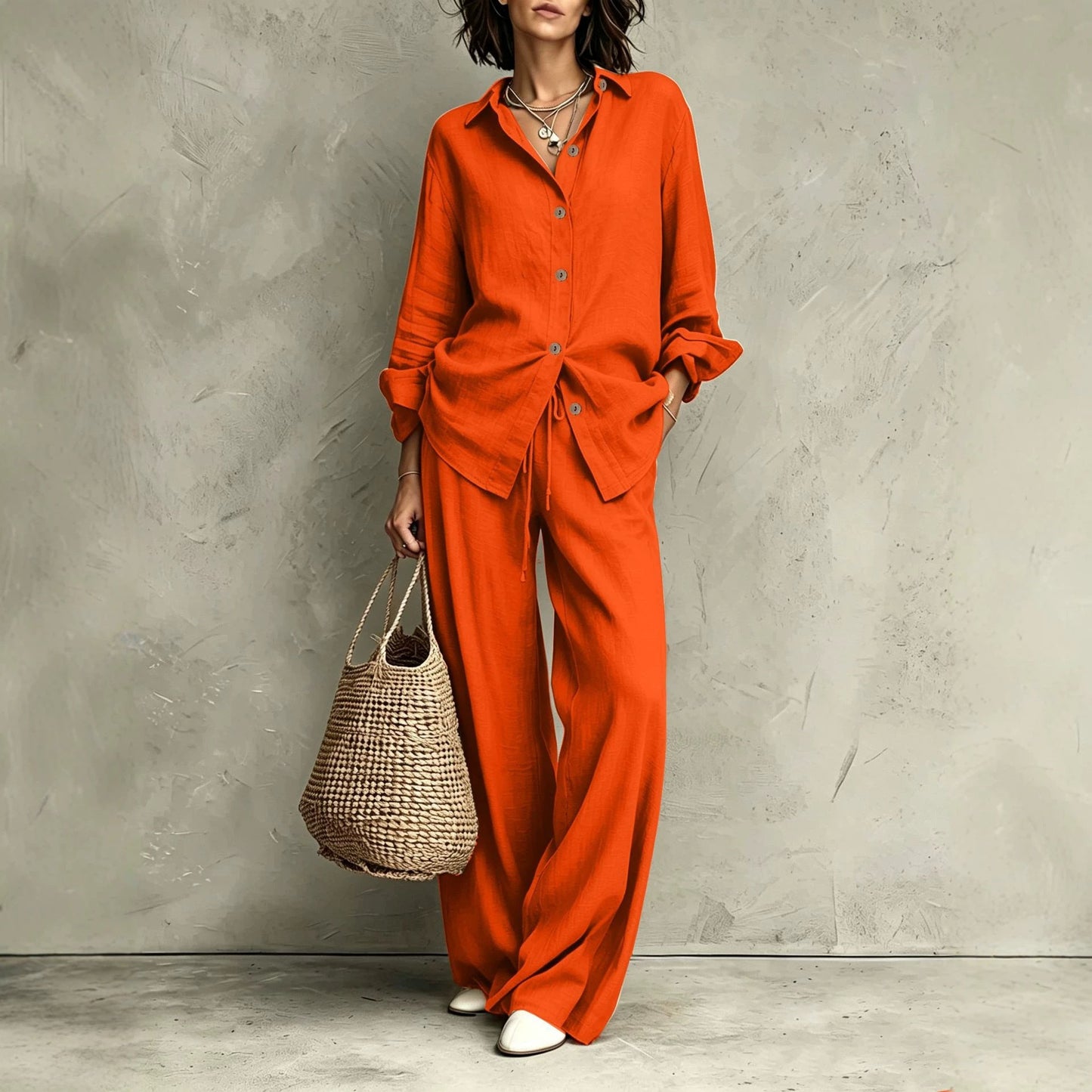 Women's button-down shirt and wide-leg pants set in orange-red – full outfit front view showing relaxed casual silhouette and straw bag