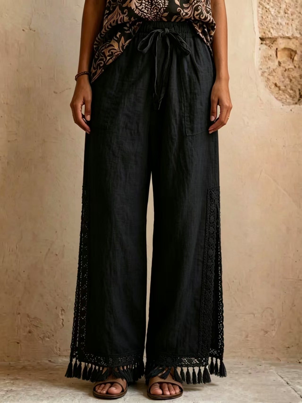 Women's bohemian lace tassel wide-leg pants in black, featuring a drawstring waist, side slit with fringe trim, and a flowing silhouette.